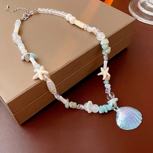 Ocean-themed beaded necklace with iridescent shell pendant and starfish detail on a display case