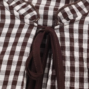 Detail of coffee plaid fabric with V-neck ruffles and coordinated tie-up ribbon closure