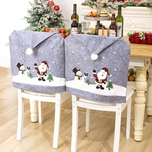 Grey Christmas chair covers with snowman and Santa prints in a cozy dining room setting