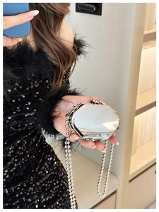 Close-up of a silver octagonal mini metal bag with a bead chain held by a model