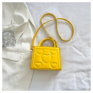 Mini sac à main jaune avec motif cœur gaufré sur tissu blanc à côté d'un blazer