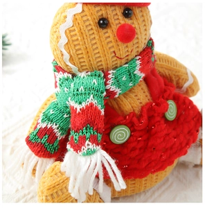 Close-up of knit Christmas gingerbread man doll with red hat and festive striped scarf