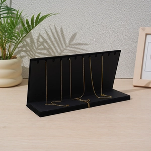 Detail of black velvet necklace display stand with 10 hooks on a wooden table