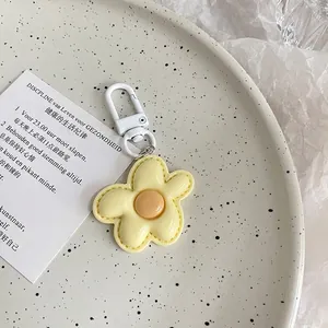 Close-up of a cute yellow flower keychain with a white matte clasp on a ceramic plate