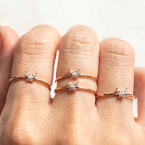 Close-up of four rose gold rings featuring butterfly shapes with clear zircon crystals