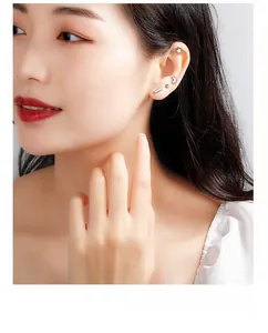 Detailed view of minimalist S999 silver stud earrings set on ear including star and moon