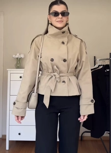 Détail d'un trench-coat court kaki à double boutonnage avec ceinture et épaulettes
