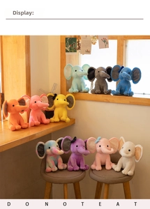 Various colorful plush elephants on a wooden desk in a bright room setting