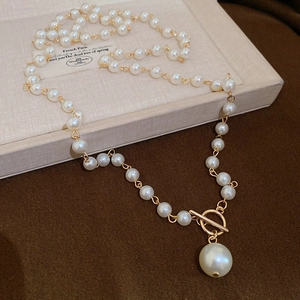 Détail du fermoir à bascule OT doré et du pendentif perle sur un collier élégant