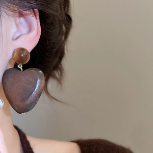 Gros plan de boucles d'oreilles cœur en bois rétro avec perles d'ambre sur modèle