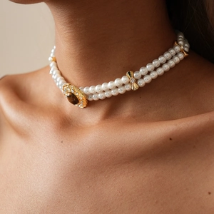 Macro detail of a double-layered pearl choker with a vintage gold tiger eye stone pendant