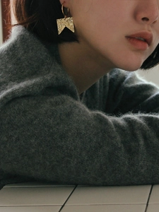 Detailed close-up of matte gold irregular flag-shaped earrings with hammered texture