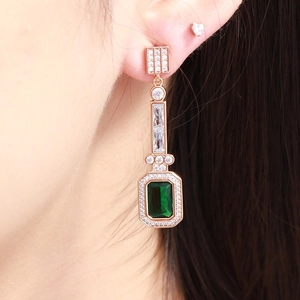 Detailed macro view of emerald teardrop earrings with rose gold and pavé diamonds