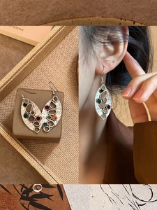 Gros plan de boucles d'oreilles vintage argentées avec design évidé et gemmes colorées
