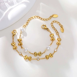 Detail of golden stainless steel girls' bracelet with pearl, zircon, and bow charm