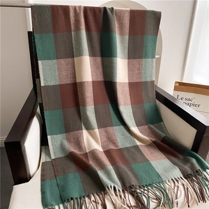 Detailed texture of green and brown plaid scarf with fringe on a wooden chair