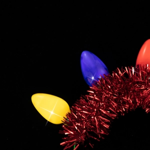Close-up of vibrant large LED bulb headband with metallic red tinsel on dark background