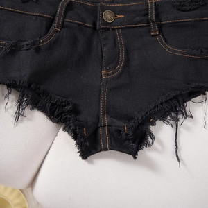 Dettaglio di shorts in denim nero a vita bassa con cuciture a contrasto e orlo sfrangiato