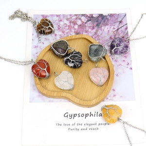Detailed wire-wrapped heart-shaped crystal pendants with tree of life design on wooden tray