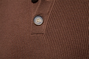 Macro view of dark brown ribbed knit fabric with wood grain button detail on the collar