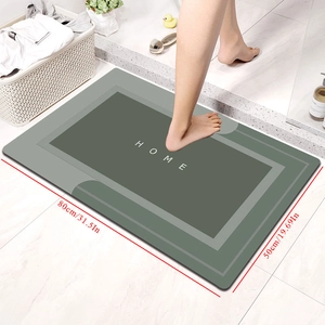 Detail of green absorbent bath mat with HOME text and 80x50cm dimensions on tile