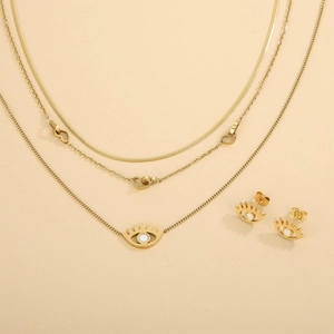 Detail of gold layered necklace set with heart and evil eye pendants and matching earrings