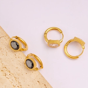 Macro detail of 18K gold-plated geometric earrings with black and clear oval zircons