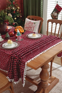 Festive red and black plaid Christmas tablecloth featuring delicate white pom-pom fringe edge