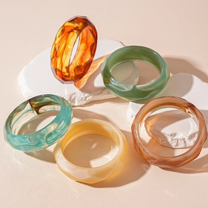 Retro acrylic geometric bangles in multiple colors displayed on decorative white stones