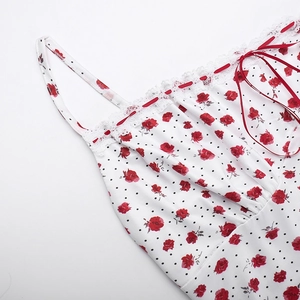 Detalle de tela blanca con rosas rojas, lunares negros, borde de encaje y lazo rojo