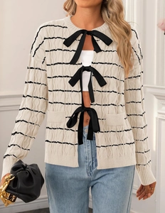 Close-up of cream knit cardigan with black stripes and three satin bow tie closures