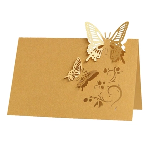 Macro detail of laser-cut golden butterfly table card with intricate floral hollow pattern