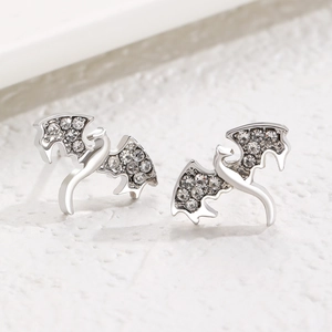 Vue macro de boucles d'oreilles dragon argentées avec des ailes en zircone cubique