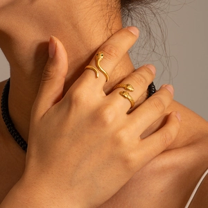 Close-up of gold snake ring with green stone eyes and textured scales on a model hand