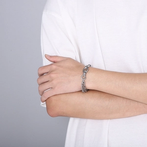 Detail of silver titanium steel chain link bracelet worn on wrist over white shirt