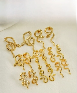Detailed collection of 18K gold plated snake-shaped earrings and studs on beige fabric