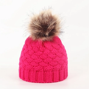 Close-up of baby winter knit hat with rose red cable pattern and brown faux fur pompom
