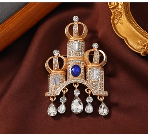 Macro view of vintage crown brooch with blue gemstone, rhinestones and drop pendants