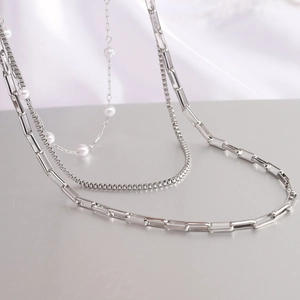 Detail of silver triple-layer necklace featuring a pearl strand and chunky paperclip chain
