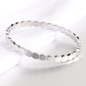 Detailed macro view of silver hexagonal honeycomb pattern on polished cuff bracelet