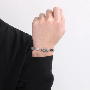 Close-up of woven titanium steel chain bracelet with white pearl and black bead accents