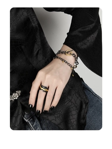 Detail shot of punk style rock texture ring and layered chain bracelets on model