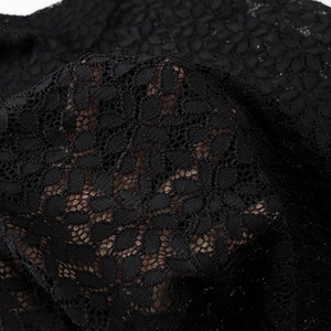 Close-up of black hollow-out crochet knit fabric showing detailed floral lace pattern