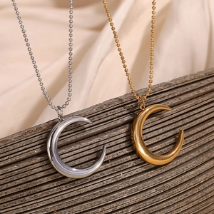 Close-up of gold and silver moon pendants with bead chains on a dark wood surface