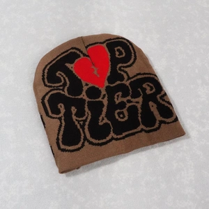 Detailed texture of brown knit beanie featuring black Top Tier text and red broken heart