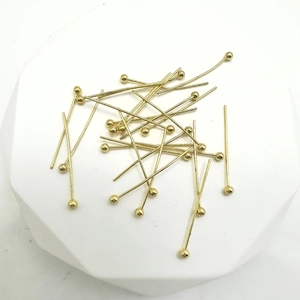 DIY jewelry making ball head pins in gold plated copper scattered on white display base