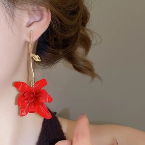 Detail of elegant red floral drop earrings with golden leaves on a female model