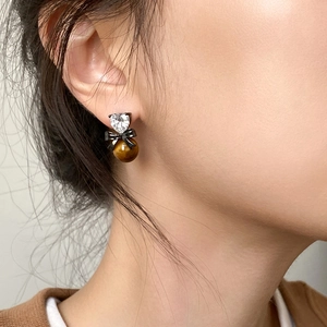 Retro heart zircon tiger eye earrings with black bow detail worn by a model