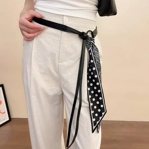 Détail d'une ceinture en cuir avec un nœud en foulard de soie imprimé noir et blanc