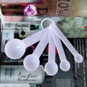 Detailed set of 5 white plastic measuring spoons with capacity markings on handles